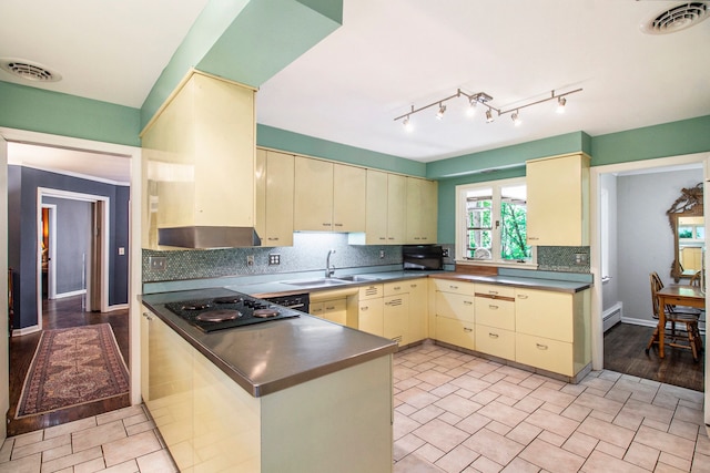 kitchen with cream cabinetry, decorative backsplash, black electric cooktop, and sink