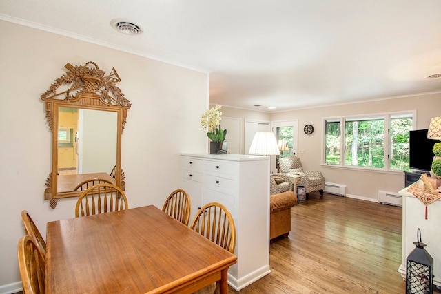 dining area featuring ornamental molding, light wood-type flooring, and a baseboard heating unit