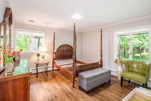 bedroom featuring baseboard heating, ornamental molding, and hardwood / wood-style flooring