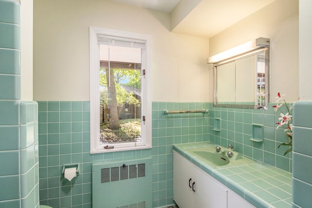 bathroom with radiator heating unit, vanity, and tile walls