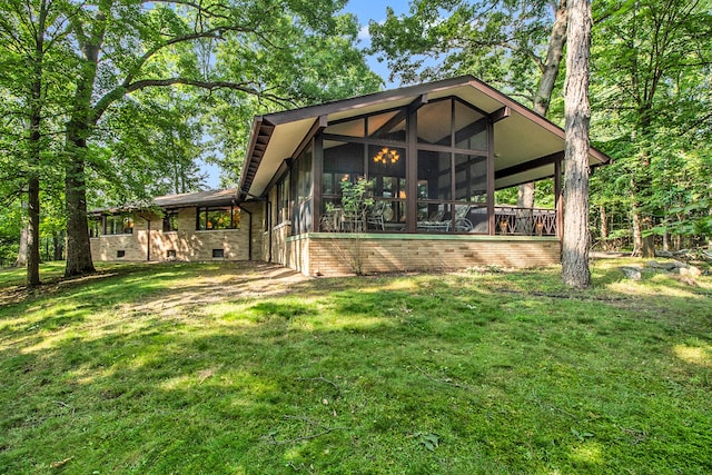 rear view of house featuring a lawn and a sunroom