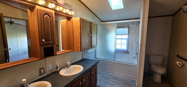 full bathroom featuring ceiling fan, lofted ceiling with skylight, bath / shower combo with glass door, a textured ceiling, and toilet