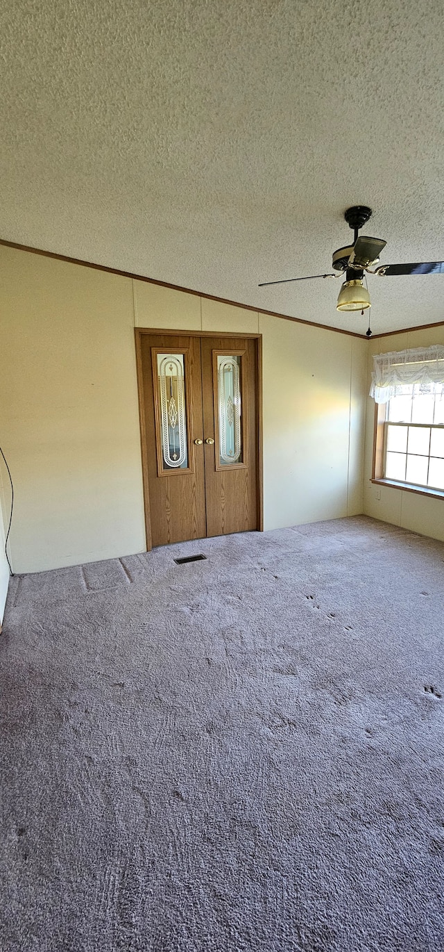 interior space featuring carpet flooring, a textured ceiling, and ceiling fan