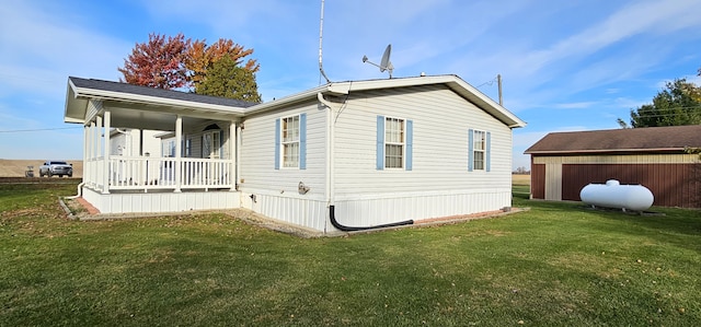 rear view of house featuring covered porch, a yard, and an outbuilding