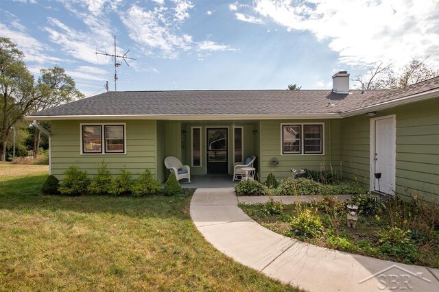 4029 Cobblestone Ct, Beaverton, MI 48612 - ranch-style home featuring a front lawn, a chimney, covered porch, and roof with shingles