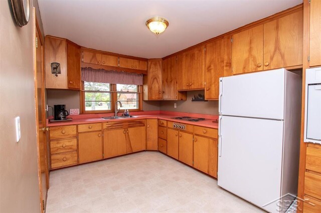 4029 Cobblestone Ct, Beaverton, MI 48612 - kitchen featuring freestanding refrigerator, a sink, light flooring, brown cabinets, and electric stovetop
