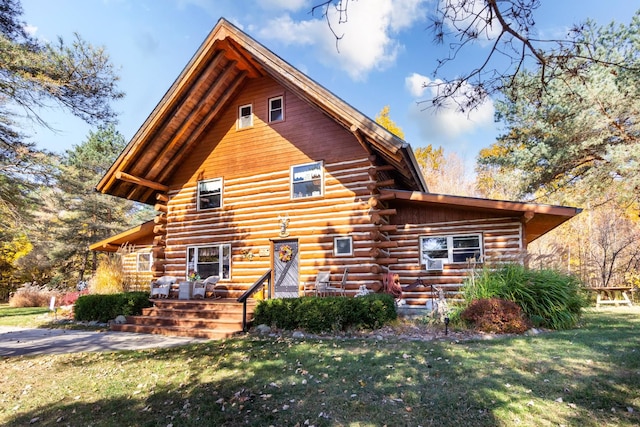 back of property featuring log siding and a lawn