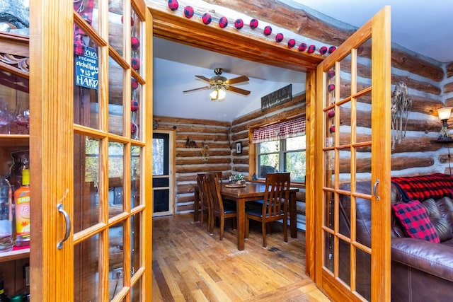 dining room with ceiling fan, french doors, log walls, hardwood / wood-style floors, and vaulted ceiling