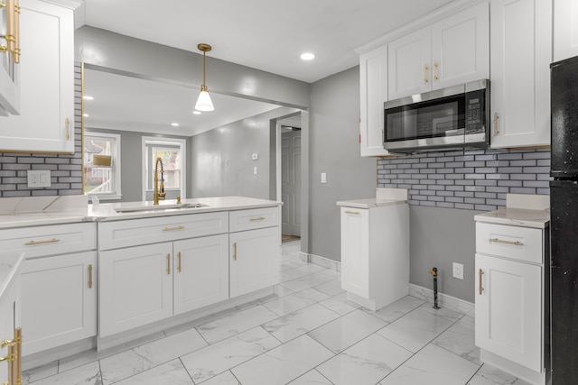 kitchen featuring tasteful backsplash, white cabinetry, sink, and pendant lighting