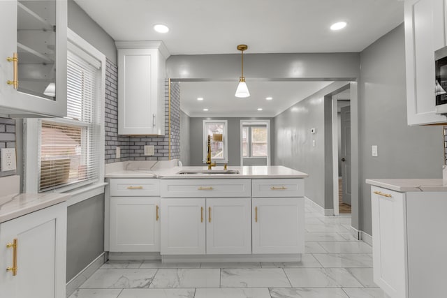 kitchen with white cabinets, light stone counters, a wealth of natural light, and hanging light fixtures