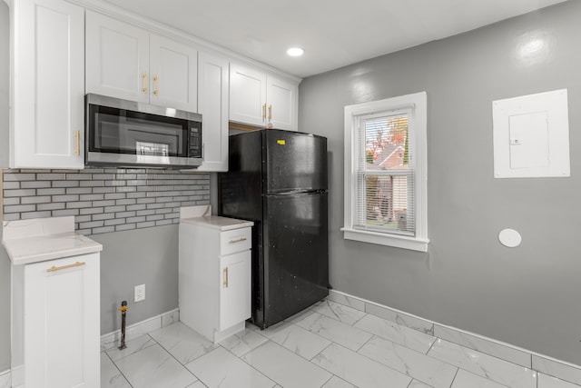 kitchen with black refrigerator, backsplash, electric panel, and white cabinetry