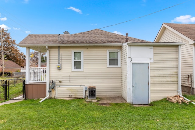 rear view of property with cooling unit and a lawn