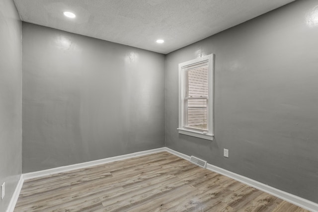 empty room featuring a textured ceiling and light hardwood / wood-style flooring