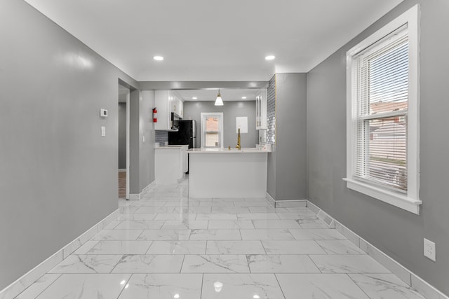 kitchen with white cabinets, stainless steel fridge, and kitchen peninsula