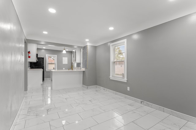 kitchen featuring black refrigerator, kitchen peninsula, white cabinetry, and sink