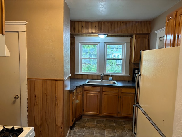 kitchen with wood walls, sink, and white refrigerator