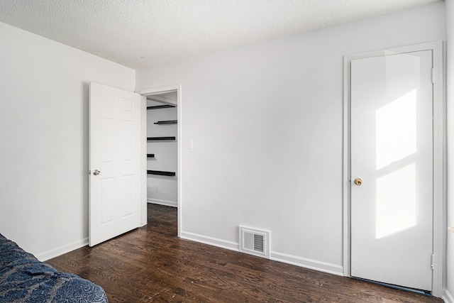 unfurnished bedroom with dark hardwood / wood-style flooring and a textured ceiling