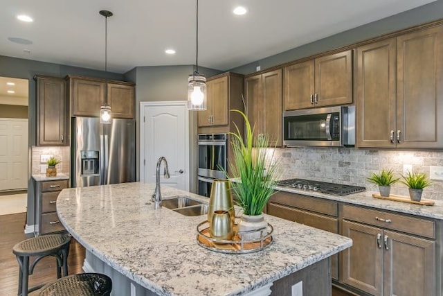 kitchen with stainless steel appliances, sink, a kitchen island with sink, and pendant lighting