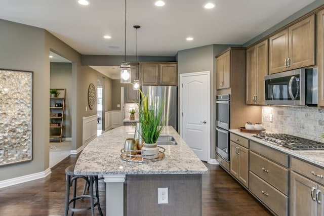 kitchen with pendant lighting, stainless steel appliances, a center island, and light stone counters