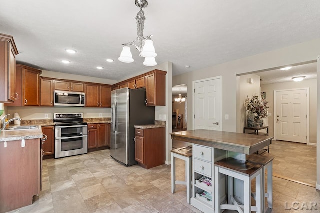 kitchen with sink, stainless steel appliances, an inviting chandelier, a textured ceiling, and decorative light fixtures