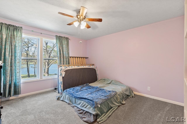 carpeted bedroom with a textured ceiling, a water view, and ceiling fan