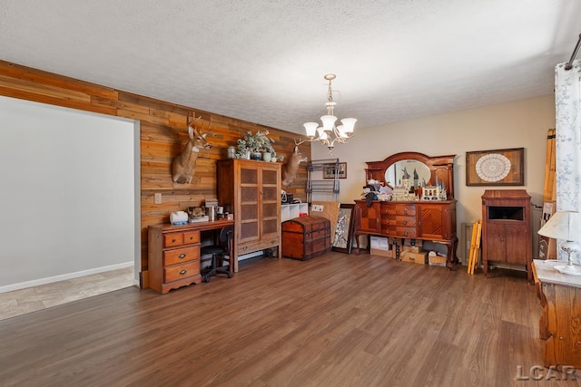 office featuring a textured ceiling, a notable chandelier, dark wood-type flooring, and wood walls