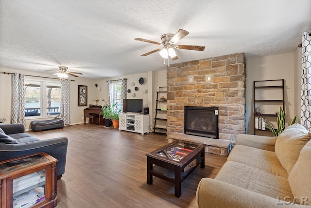 living room featuring ceiling fan, a fireplace, dark wood-type flooring, and a textured ceiling