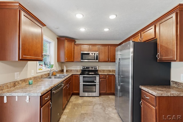 kitchen featuring light stone countertops, appliances with stainless steel finishes, a textured ceiling, and sink