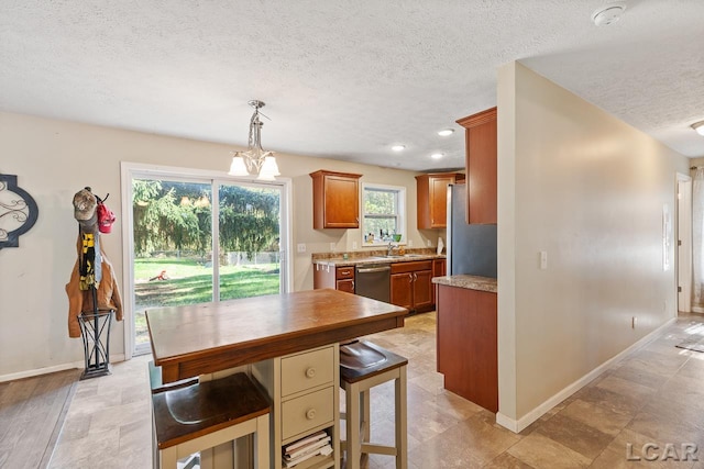 kitchen featuring a kitchen breakfast bar, a textured ceiling, stainless steel appliances, sink, and pendant lighting