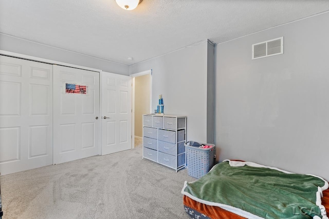 bedroom featuring a textured ceiling, light carpet, and a closet