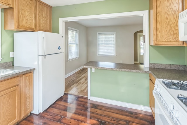 kitchen featuring kitchen peninsula, dark hardwood / wood-style flooring, and white appliances