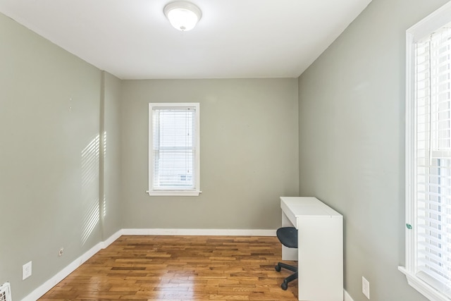 unfurnished office featuring hardwood / wood-style floors and a healthy amount of sunlight