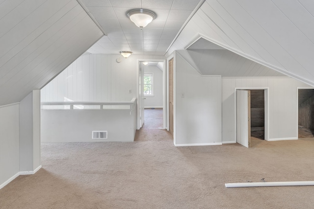 bonus room featuring light carpet, lofted ceiling, and wood walls