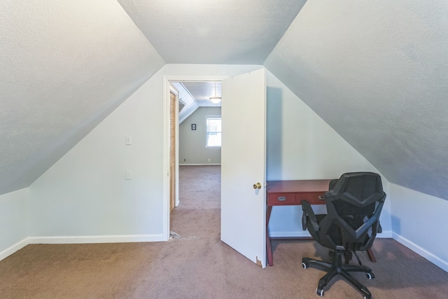 carpeted office space featuring a textured ceiling and lofted ceiling