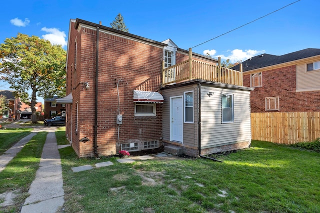 rear view of house featuring a balcony and a lawn