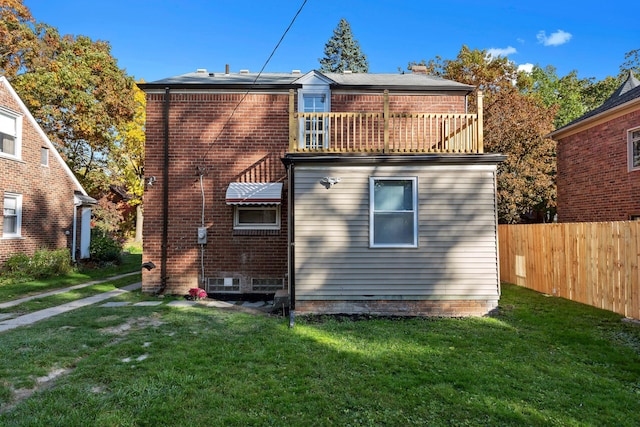 rear view of house featuring a lawn and a balcony