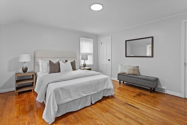 bedroom with wood-type flooring, vaulted ceiling, and ornamental molding