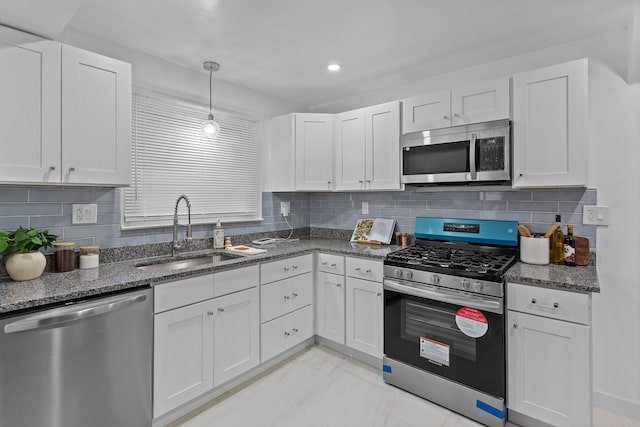 kitchen featuring stainless steel appliances, white cabinetry, dark stone countertops, and sink