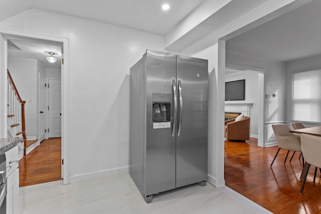 kitchen with stainless steel refrigerator with ice dispenser, light hardwood / wood-style floors, and ornamental molding