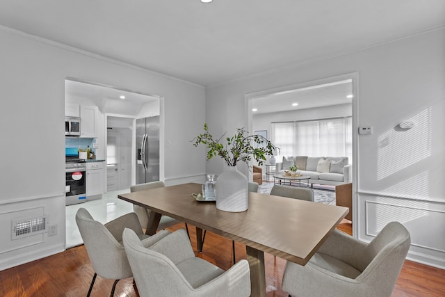 dining room with hardwood / wood-style floors and crown molding