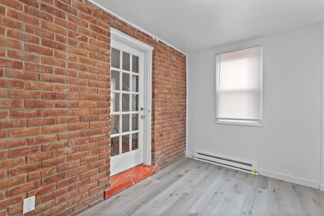 interior space with light wood-type flooring, a baseboard heating unit, and brick wall