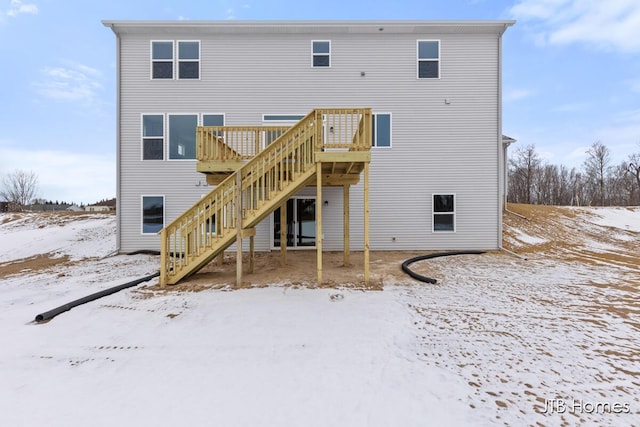 snow covered back of property with a wooden deck