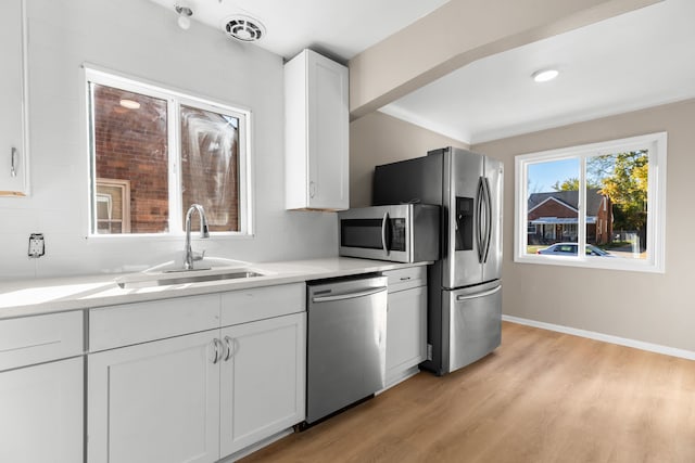 kitchen featuring backsplash, white cabinets, sink, light hardwood / wood-style floors, and stainless steel appliances