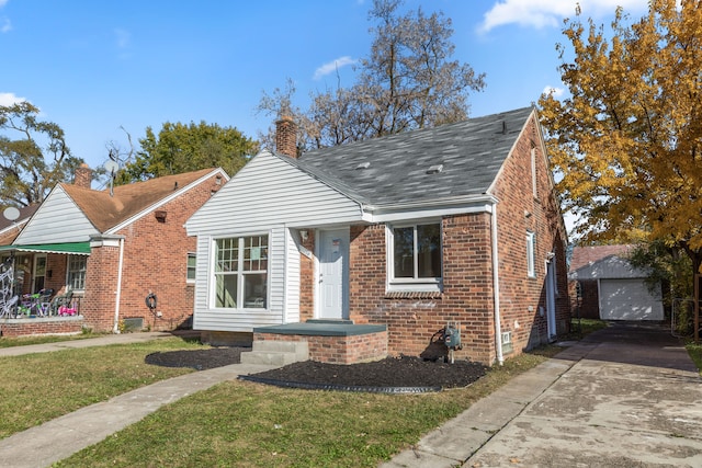 bungalow with a garage, an outbuilding, and a front yard