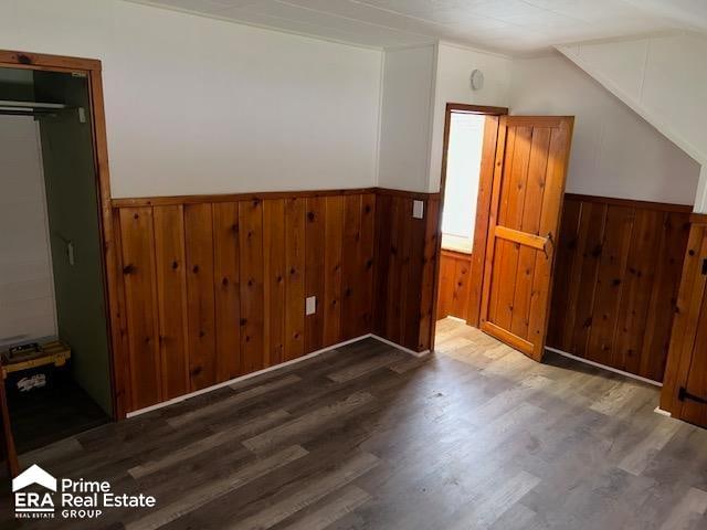 bonus room with wood walls, wood-type flooring, and lofted ceiling