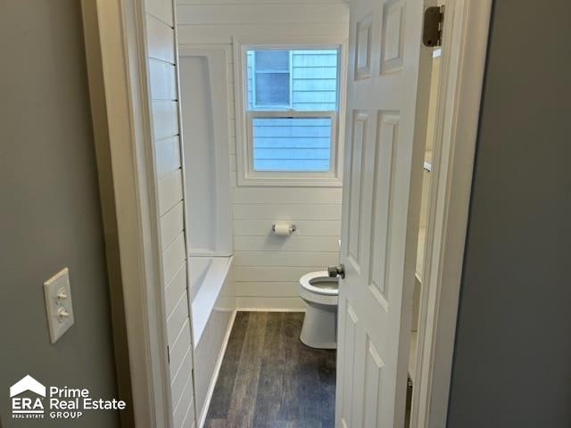 bathroom with wood-type flooring, toilet, and wooden walls