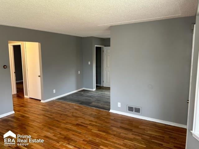 spare room featuring dark hardwood / wood-style floors and a textured ceiling