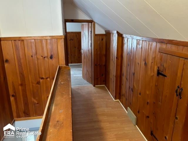 bonus room with wooden walls, light hardwood / wood-style floors, and lofted ceiling