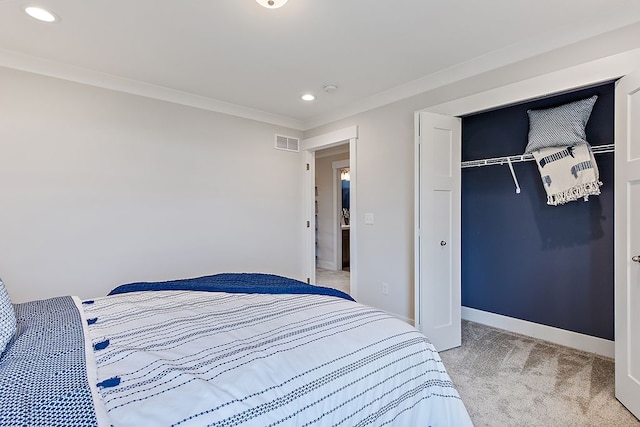 bedroom with light colored carpet, crown molding, and a closet