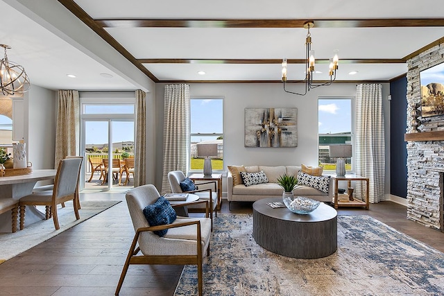 living room featuring a stone fireplace, dark hardwood / wood-style flooring, ornamental molding, and an inviting chandelier